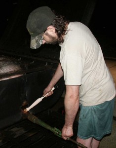 Eric Saperstein lighting the burner in Artisans of the Valley's custom made oil tank pig cooker (roaster)